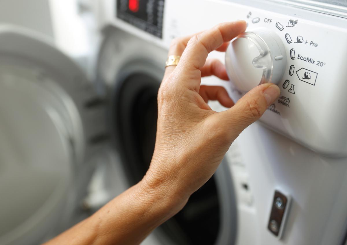 Una persona manipula una lavadora.