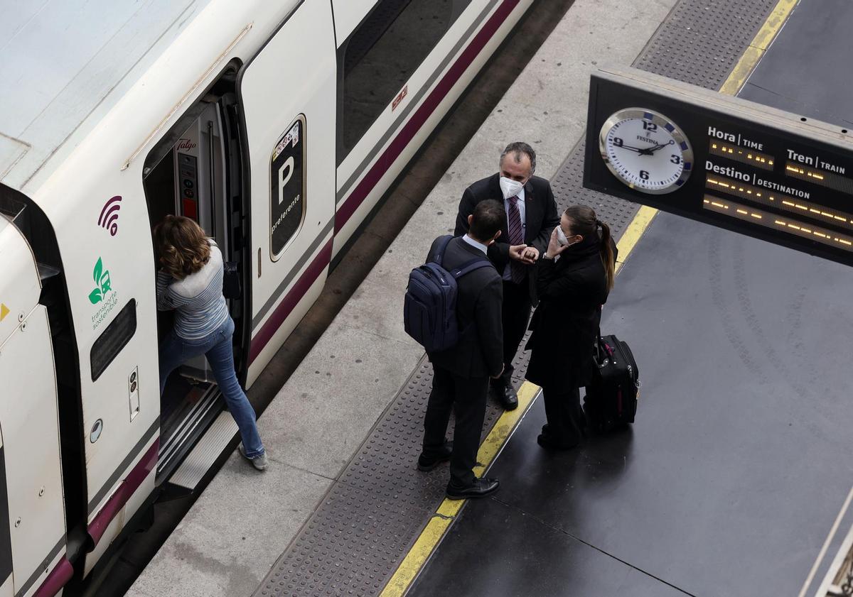 Varias personas, con maletas, en el andén antes de coger un tren de alta velocidad, en la estación Madrid - Puerta de Atocha, en Madrid.(España).
