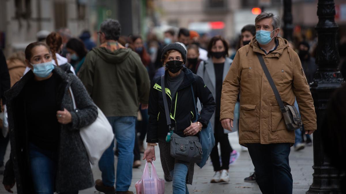 Varias personas con mascarilla pasean por una calle de Barcelona.