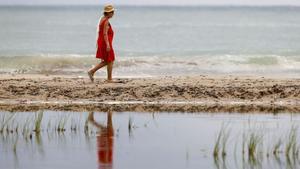 Una mujer pasea en una playa española.