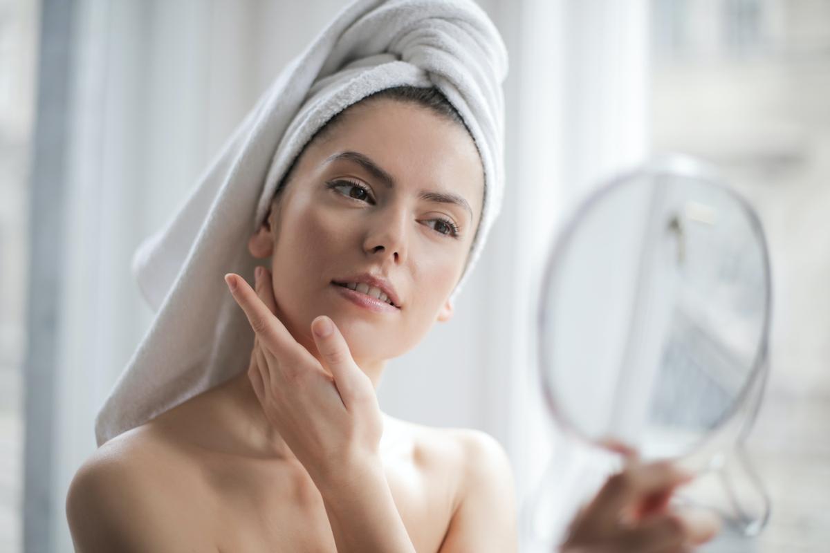 Una mujer aplicando productos de ’skincare’ sobre su rostro
