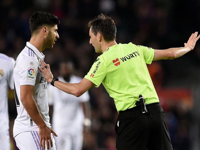 El árbitro Ricardo De Burgos Bengoetxea explica a Marco Asensio la decisión de anular su gol por fuera de juego tras la intervención del VAR.