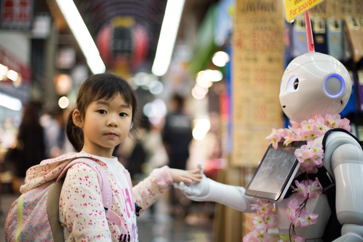 Una niña coge la mano de un robot en Ōsaka-shi, Japan.