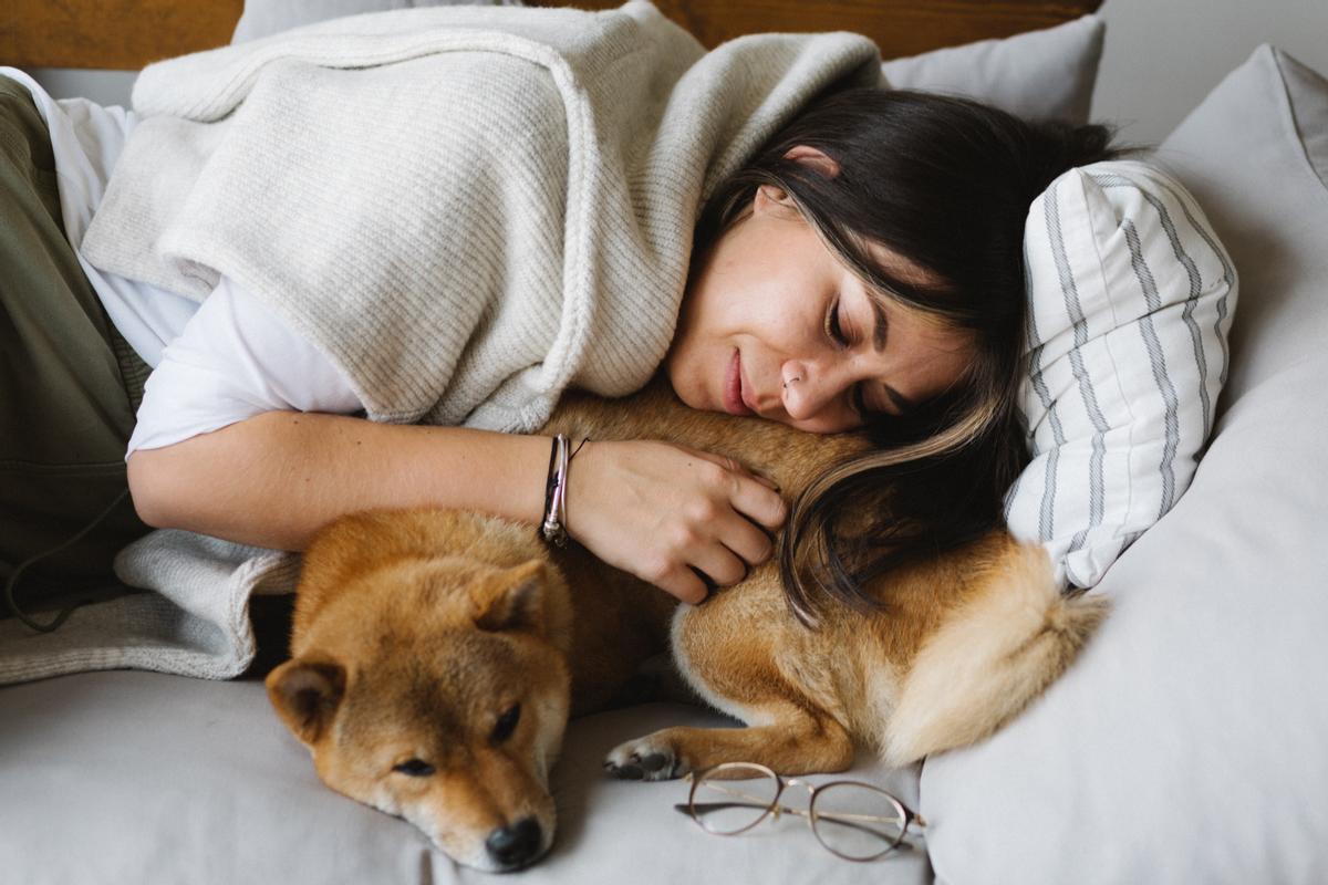 Una joven descansa sobre un sofá junto a su perro.