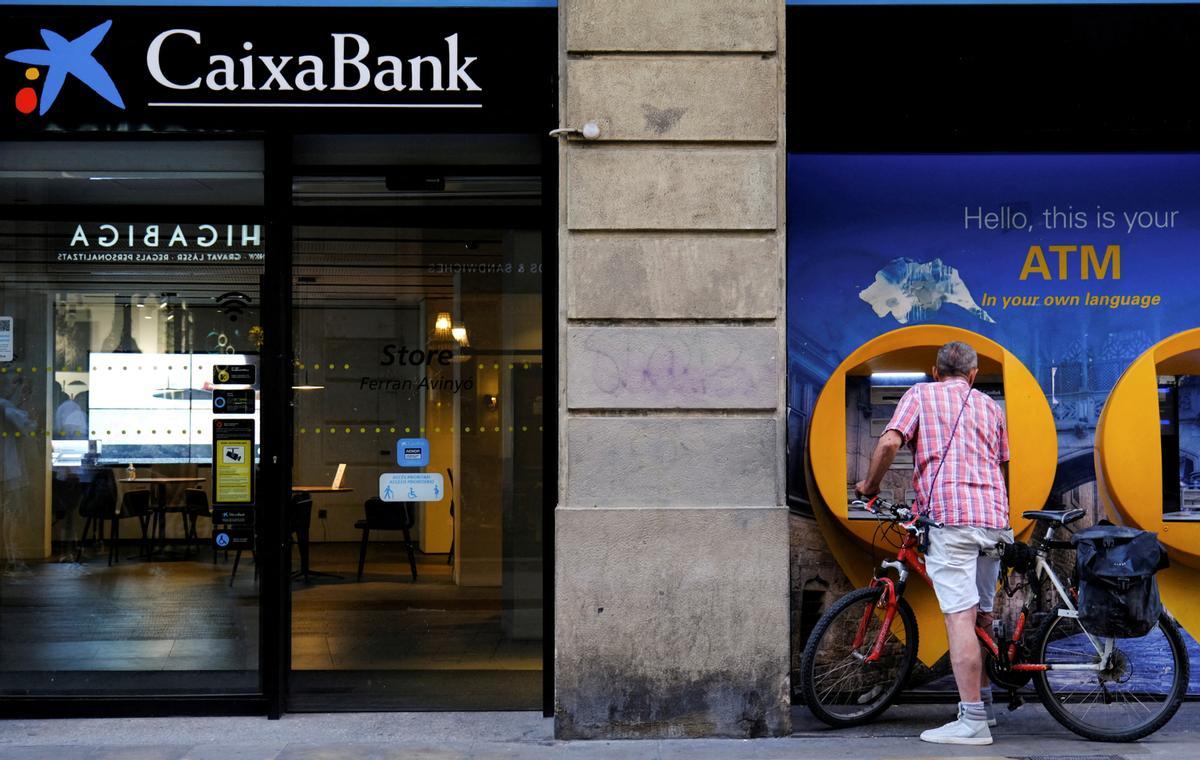 FILE PHOTO: A man uses a Caixabank ATM in Barcelona