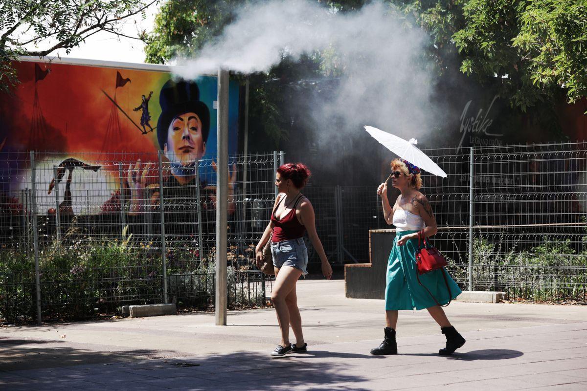 Unos turistas intentan refrescarse en unos vaporizadores de agua fresca en Barcelona.