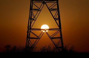 Una torre de electricidad con el sol de fondo.