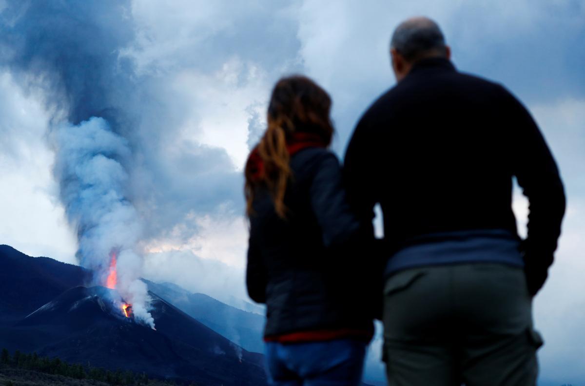 Dos personas observan el volcán de La Palma, mientras sigue expulsando lava