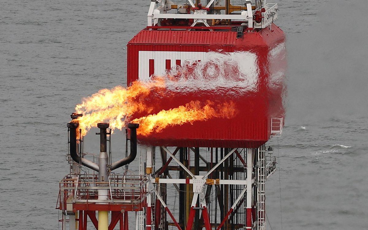 Antorcha de gas junto al cartel de la compañía Lukoil en la plataforma petrolera Filanovskogo en el Mar Caspio, en Rusia.