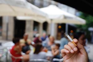 Un cliente fuma un cigarrillo en una terraza. 