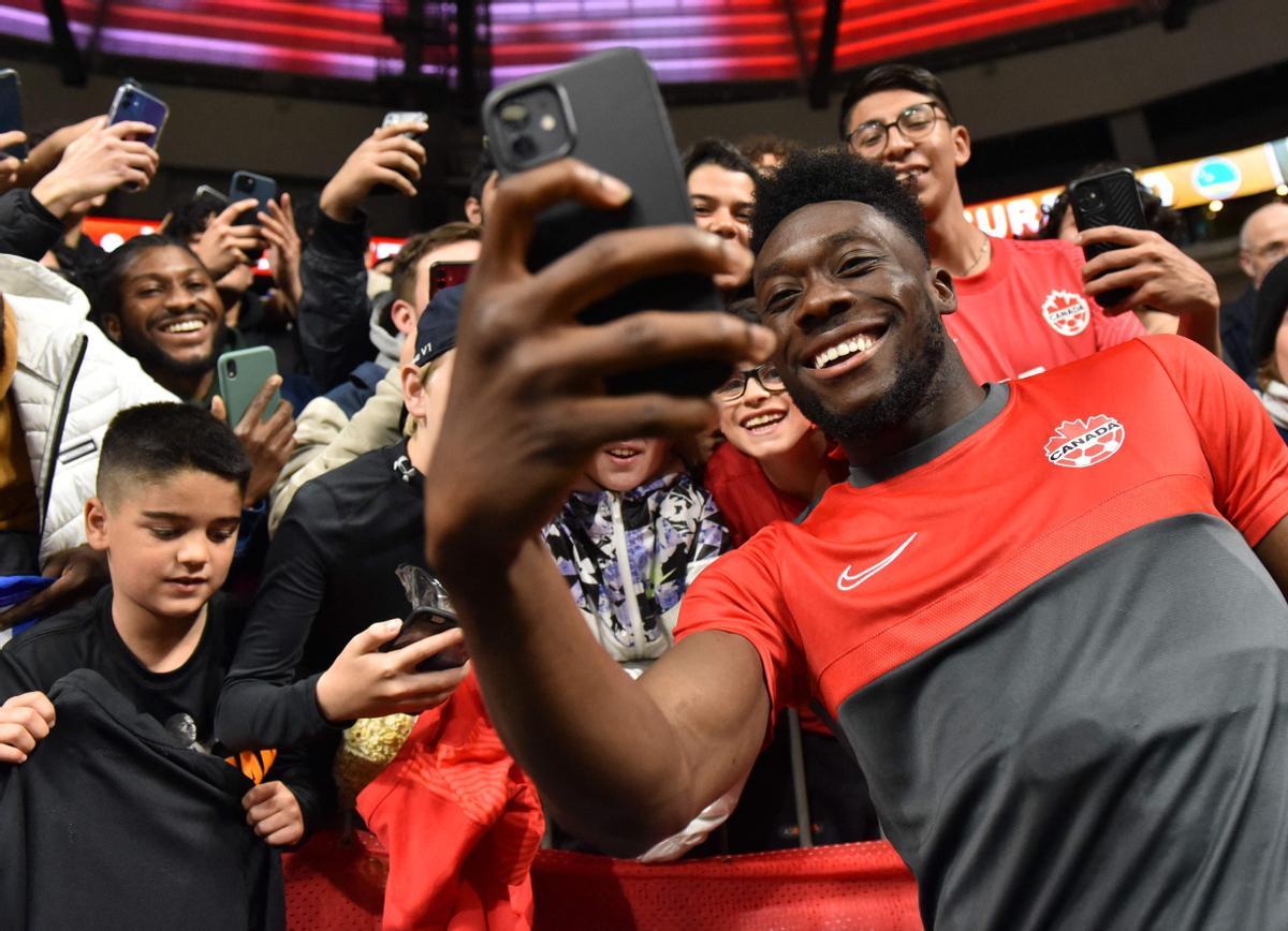 Alphonso Davies, jugador de Canadá, se hace un selfie con aficionados después de un partido.
