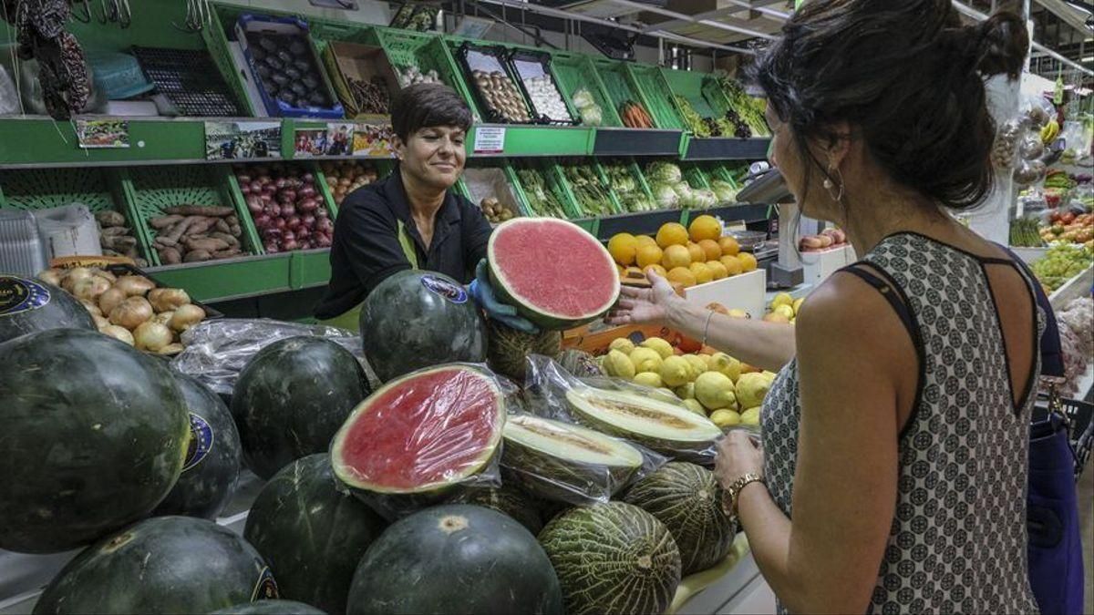 Una mujer compra sandía en una frutería. Una mujer compra sandía en una frutería.