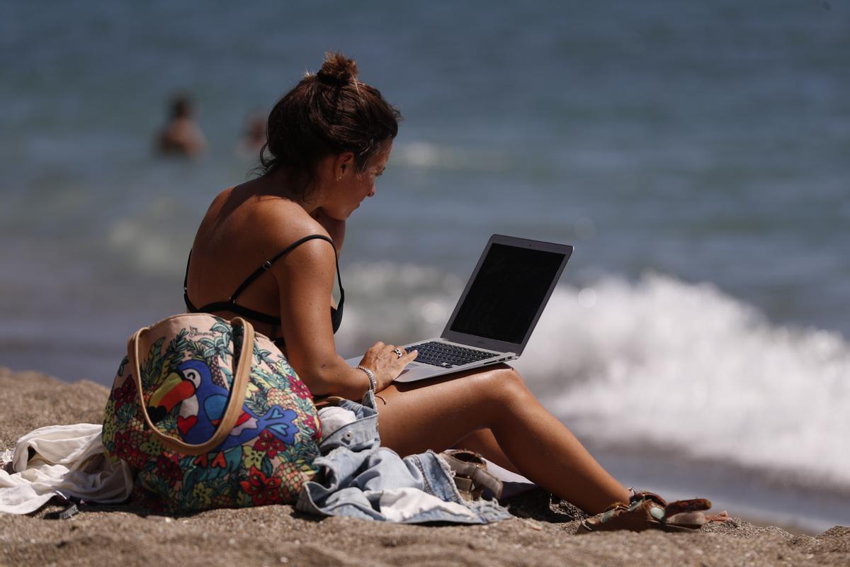 Consulta el portátil en la playa de La Malagueta el pasado octubre, con récord en los termómetros.
