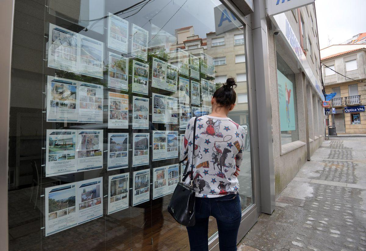 Una mujer pasa ante el escaparate de una inmobiliaria en Barcelona.