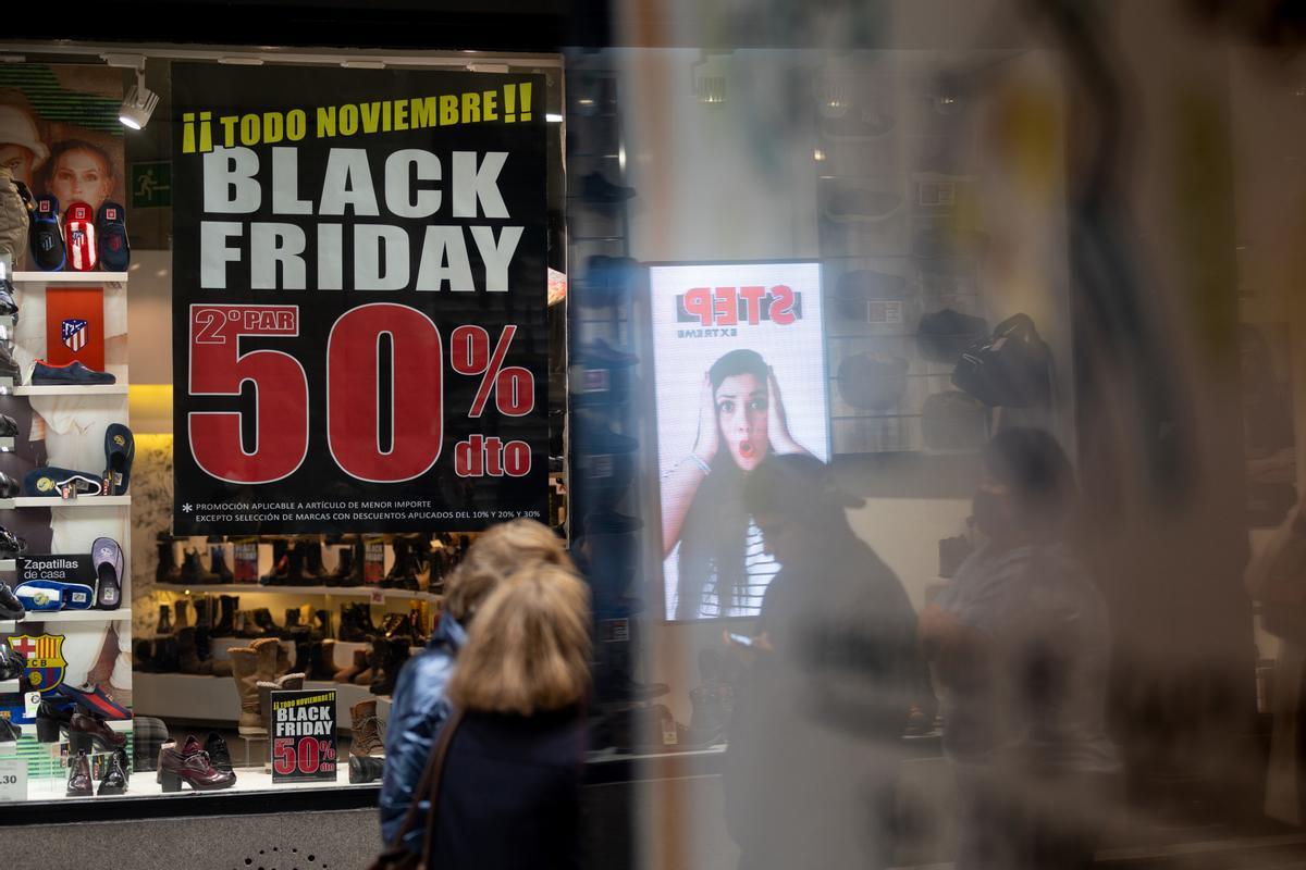 Un grupo de personas caminan frente a una tienda con ofertas por el ’Black Friday’ en Madrid.