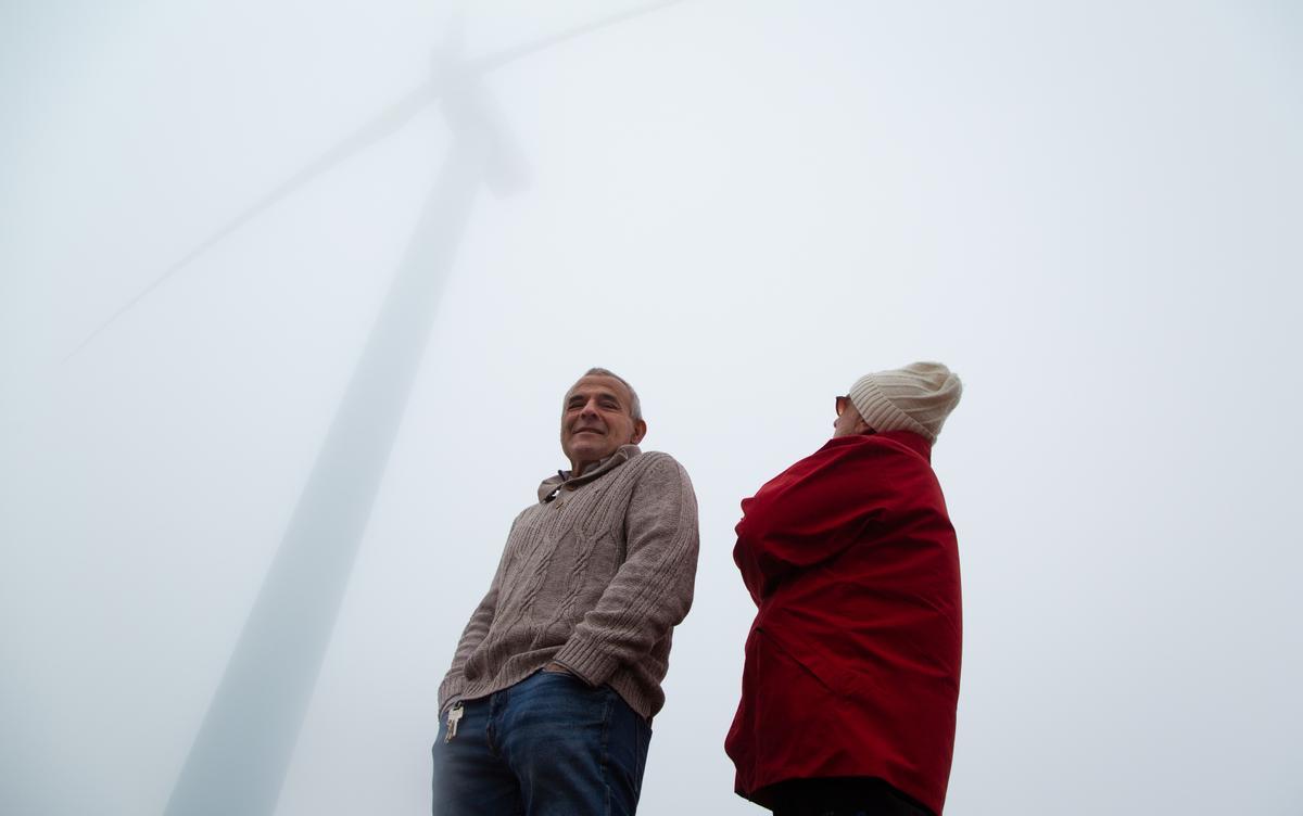 Aurelio y Javier, de la asociación ecologista La Braña, frente a un molino de la instalación eólica de El Pical. 