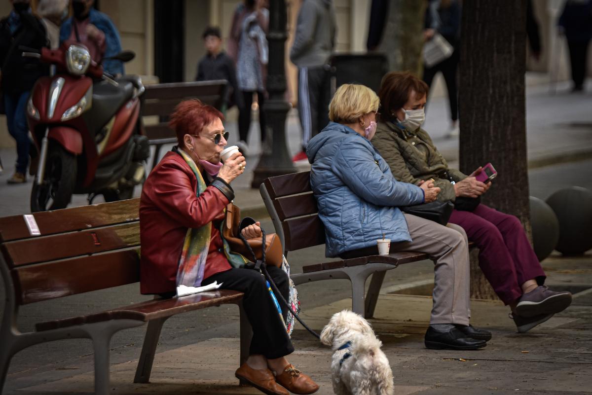 Varias ancianas se sientan en unos bancos en Barcelona. 