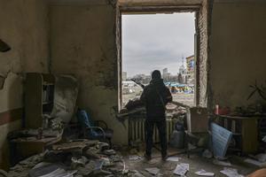 Un miliciano ucraniano con un arma custodiando un edificio destruido en Járkov.