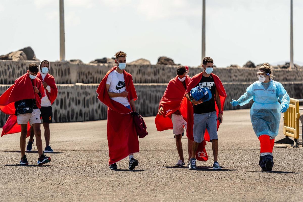 Una voluntaria de Cruz Roja atiende a dos migrantes en su llegada a Lanzarote.