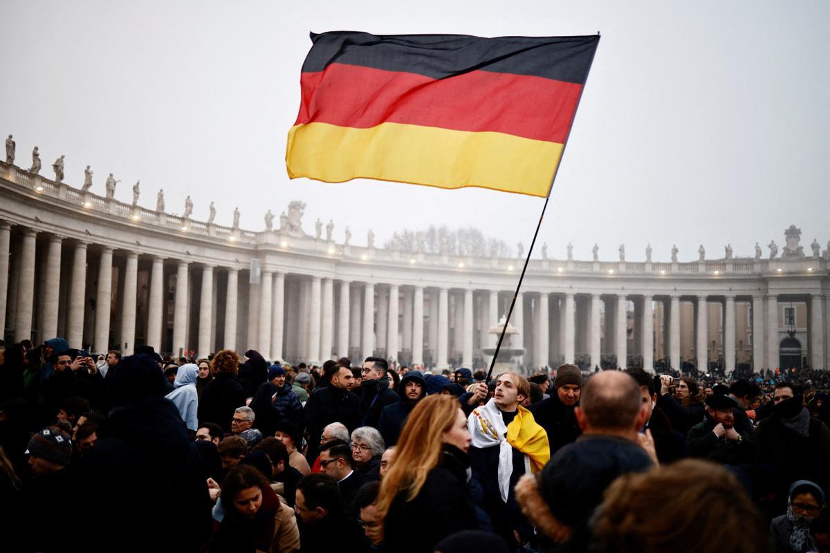 Un hombre alza una bandera alemana en El Vaticano.