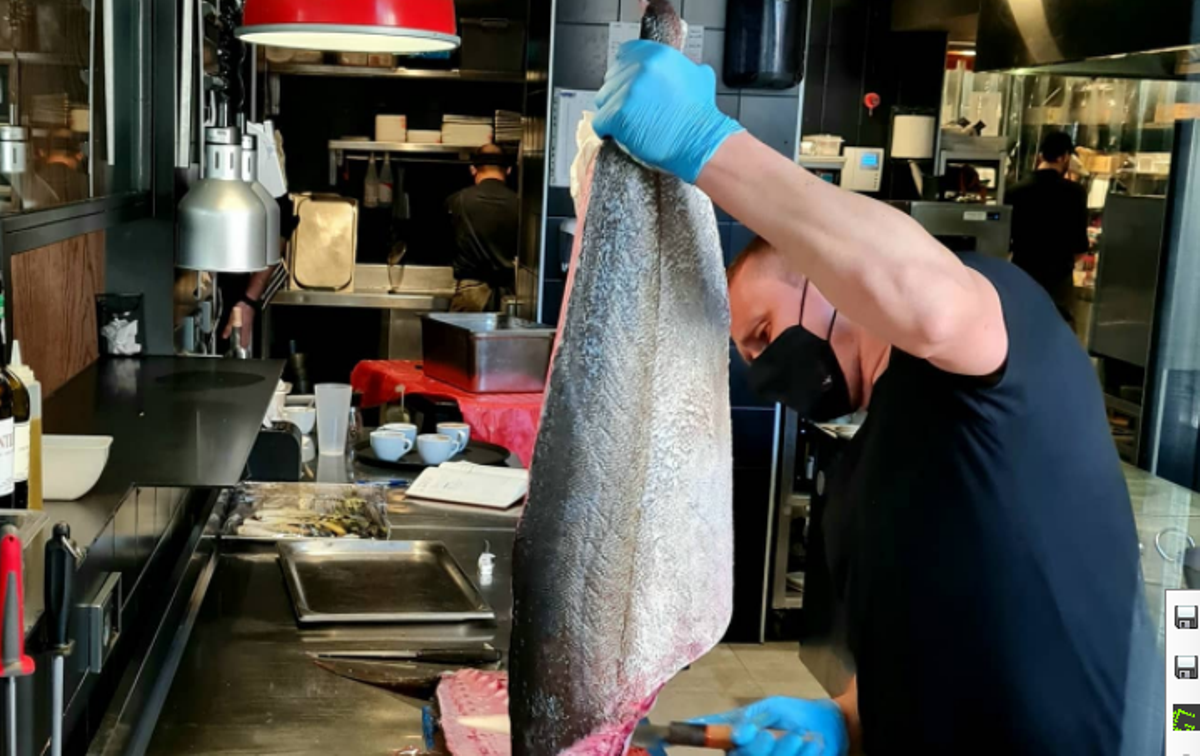 Un cocinero del restaurante Lakasa limpia un pez limón en la cocina del establecimiento, situado en Chamberí.