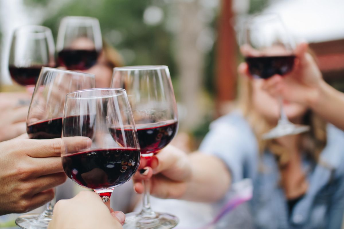 Un grupo de personas brindan con copas de vino. Un grupo de personas brindan con copas de vino.