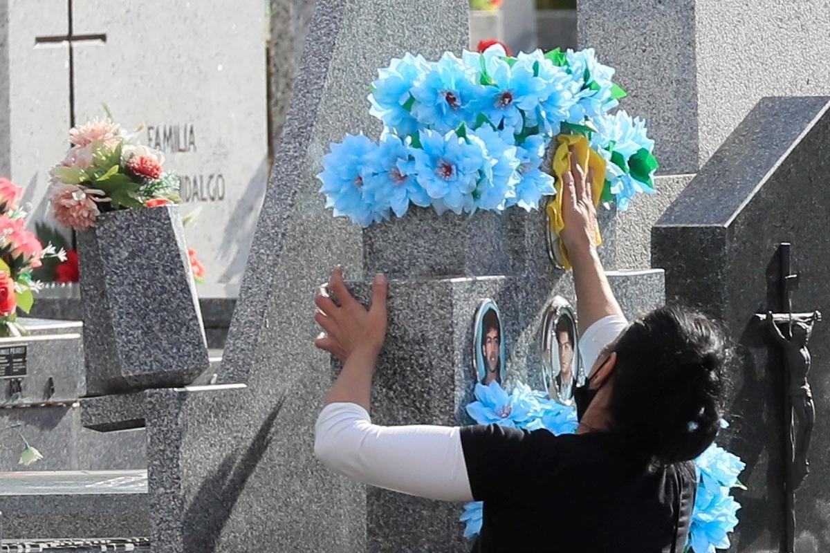 Una mujer limpia una lápida en un cementerio de La Almudena. 