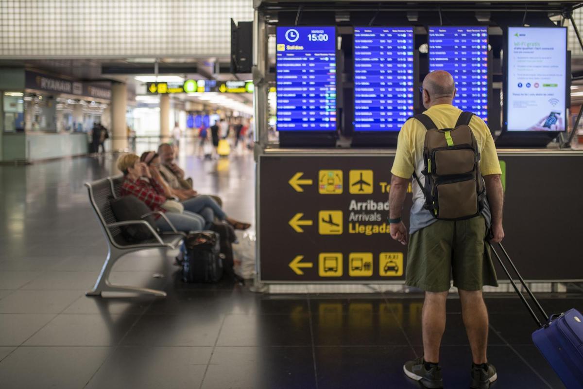 Un hombre mira un panel de llegadas y salidas en el Aeropuerto de El Prat. EP