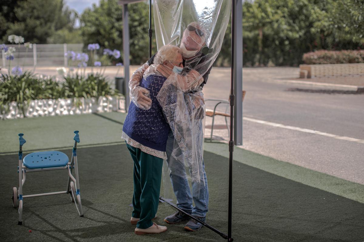 Una interna en una residencia de mayores abraza a su hijo a través de un plástico habilitado para que los familiares se puedan dar abrazos a sus familiares en pandemia.