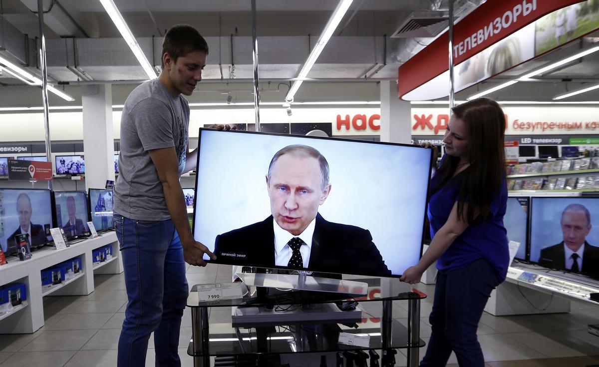 Dos empleados colocan una televisión en una tienda de electrónica en Moscú (Rusia). 3 de diciembre de 2015. 