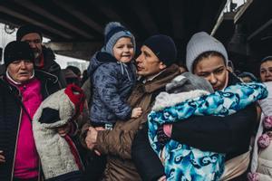 Varias personas con niños esperan para cruzar el río en Irpin (Ucrania).