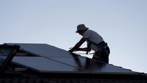 Un operario coloca paneles solares en el tejado de una vivienda unifamiliar.
