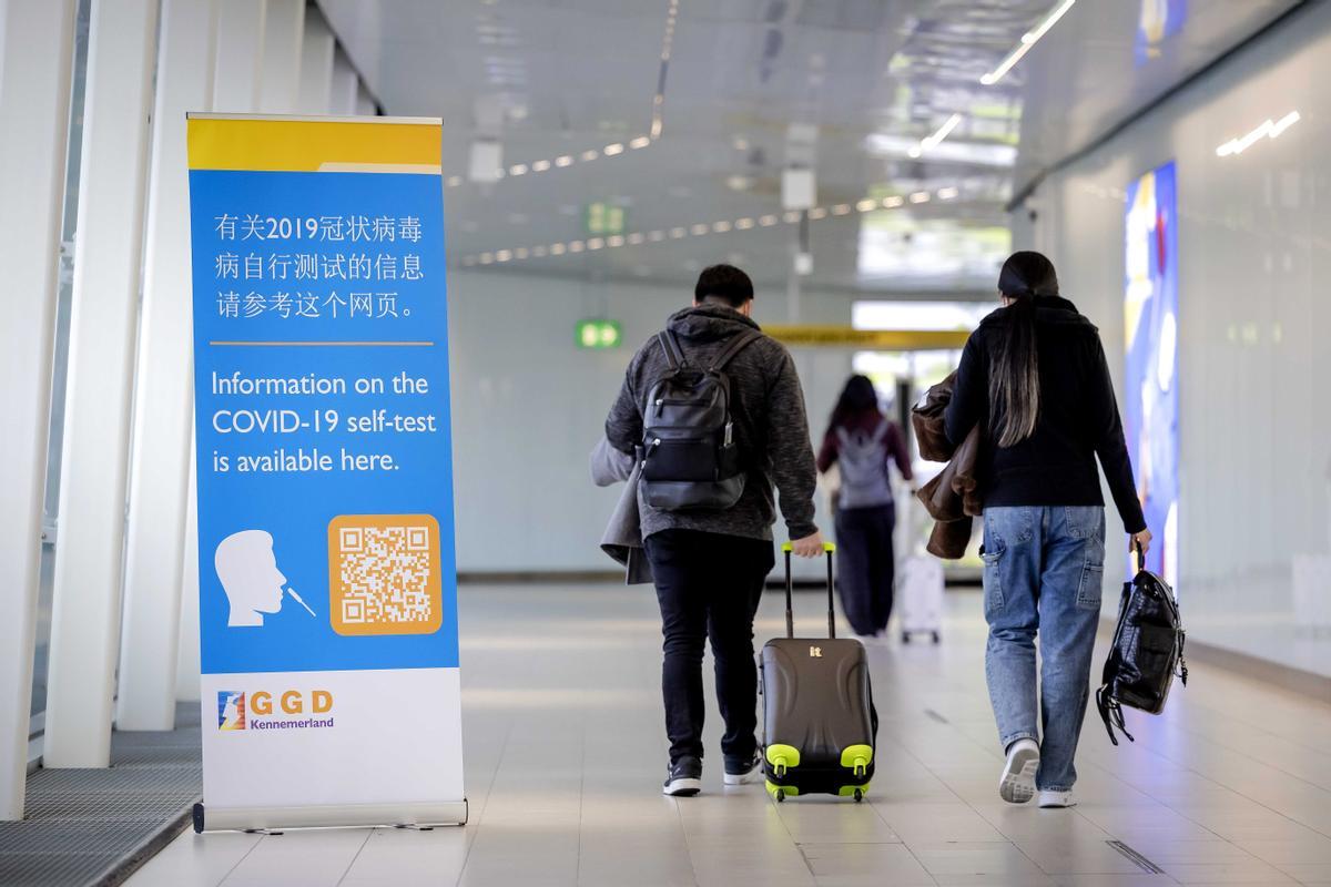 Schiphol (Netherlands), 04/01/2023.- Travelers from China walk past a banner with information and receive a free Covid-19 self-test upon arrival at Schiphol, The Netherlands, 04 January 2023. The self-tests are provided with information on how to use them in Mandarin or Cantonese. (Países Bajos; Holanda) EFE/EPA/ROBIN VAN LONKHUIJSEN
