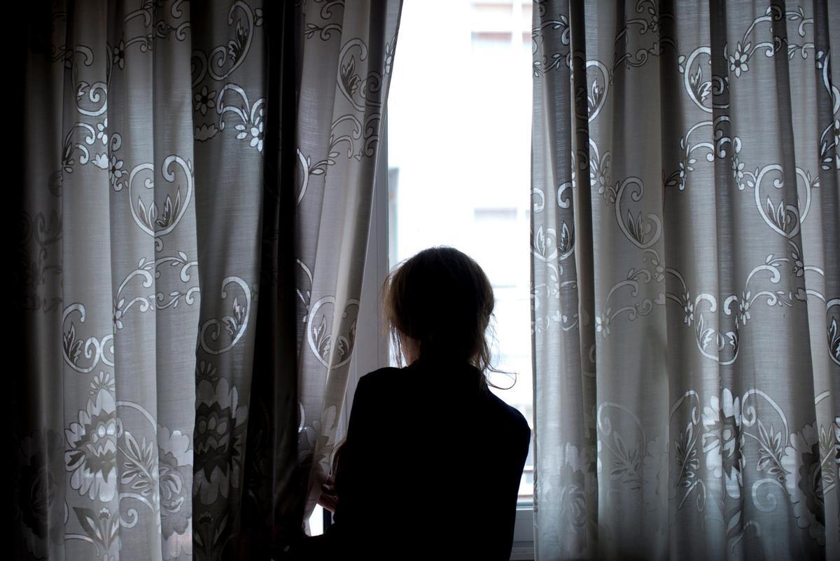 Una mujer observa a través de la ventana de su vivienda, en una imagen de archivo. EFE/Brais Lorenzo