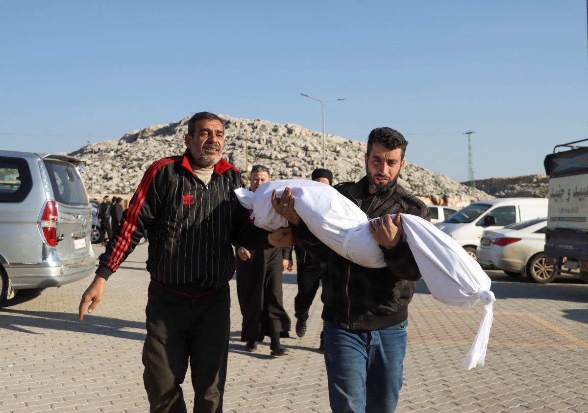 Unos hombres llevan el cuerpo de un niño sirio muerto en el terremoto.