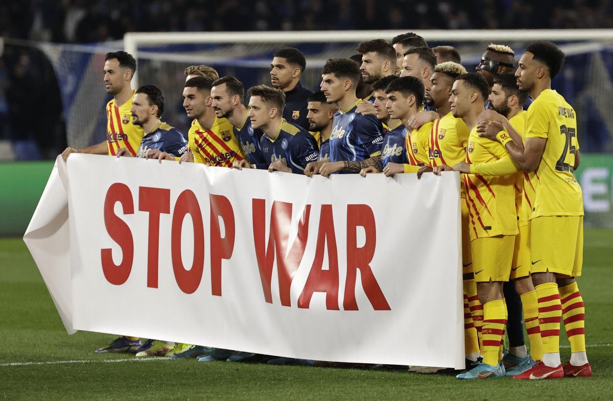 Jugadores del Barça y del Nápoles posan por una pancarta por el final de la guerra antes de su partido de este jueves.