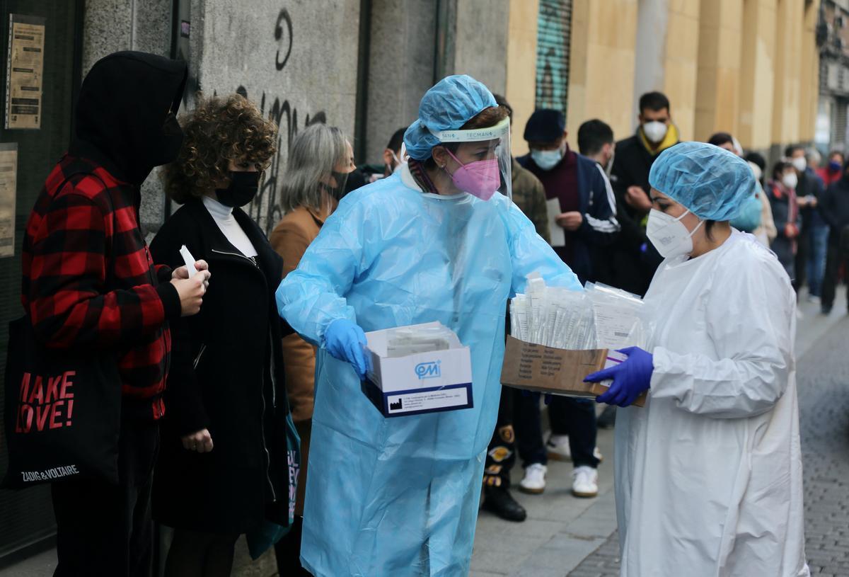 Dos sanitarias recogen test de covid-19 de las personas que hacen cola en el Centro de Salud Universidad, en Madrid.