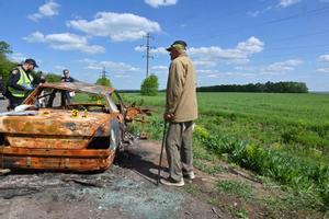 Un señor ucraniano observa los restos de un coche presuntamente atacado por la artillería rusa en Járkov, el 23 de mayo.
