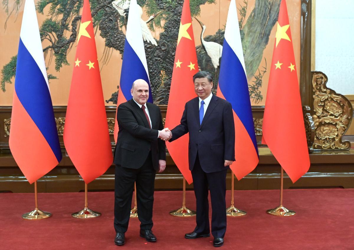 El primer ministro ruso, Mikhail Mishustin, da la mano al presidente chino Xi Jinping.