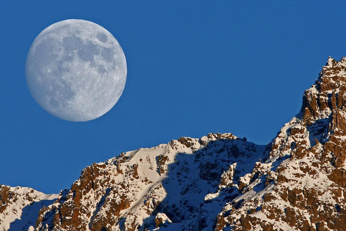 La luna llena sale tras la montaña Tijerflue en Arosa, Suiza.