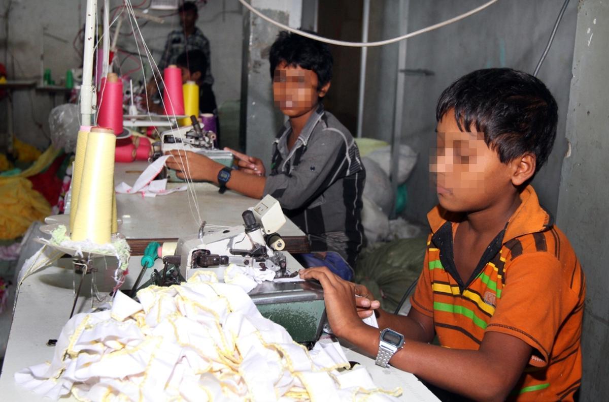 Dos niños realizan trabajos en una fábrica textil