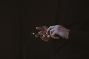 Una persona interactúa con un móvil en sus manos. 