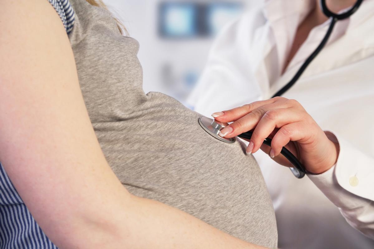 Una sanitaria examina a una mujer embarazada.