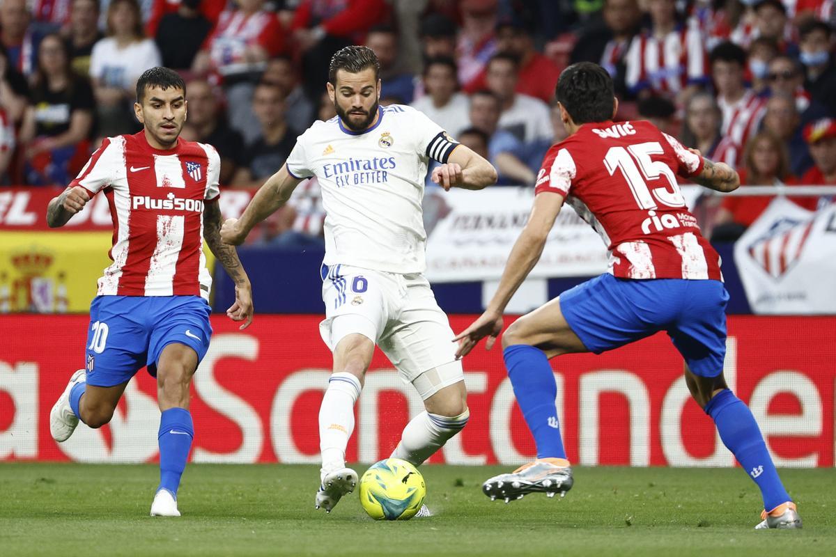 El defensa del Real Madrid Nacho Fernández (c) intenta superar al montenegrino Stefan Savic (d), del Atlético de Madrid, durante el partido de la jornada 35 de Liga en Primera División que Atlético de Madrid y Real Madrid de este domingo.
