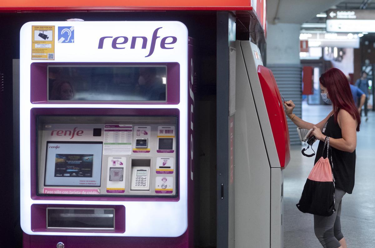 Una mujer compra su billete en las taquillas de venta automática de la estación de tren de Atocha.