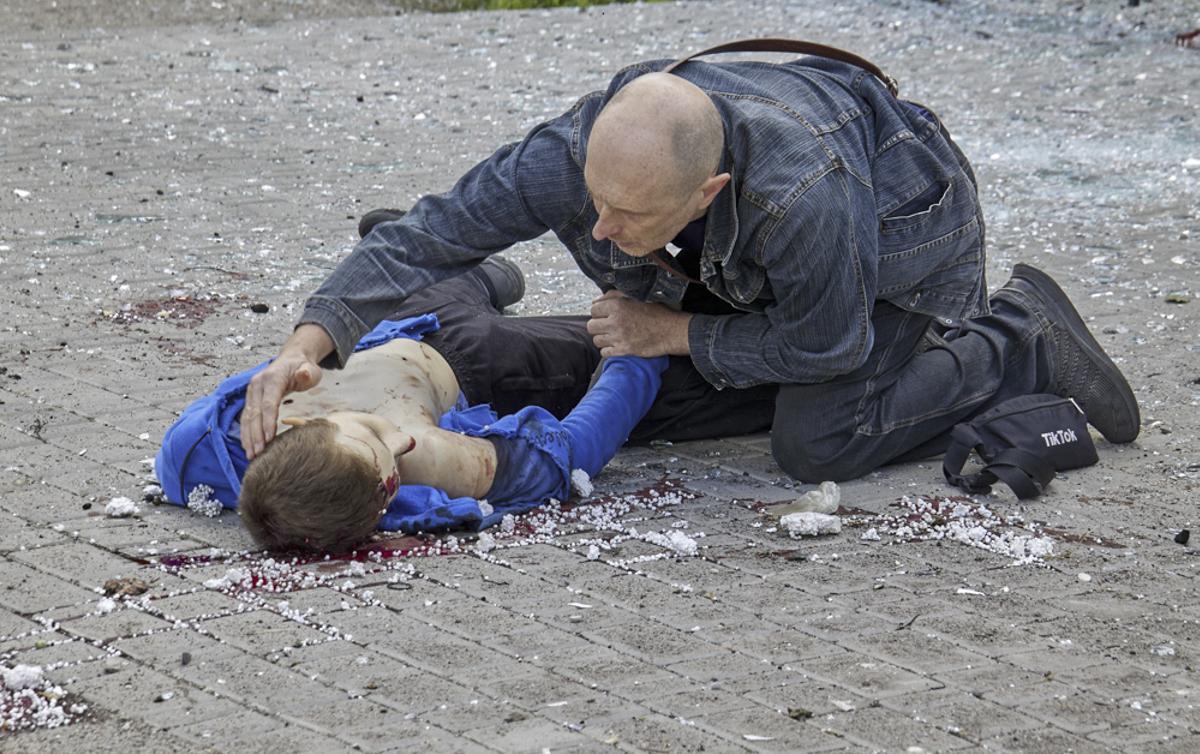 Un hombre se arrodilla ante el cadáver de un niño muerto en un bombardeo ruso contra una parada de autobús en Járkov, el 20 de julio de 2022.