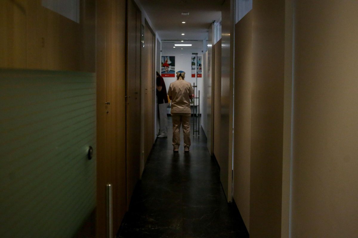 Un trabajador pasa por un pasillo de un centro de salud. Un trabajador pasa por un pasillo de un centro de salud.