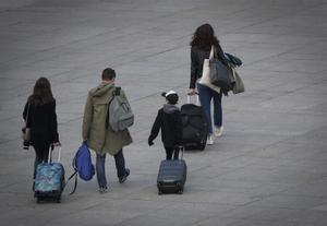 Una familia carga con su equipaje en la céntrica Plaza del Castillo de Pamplona.