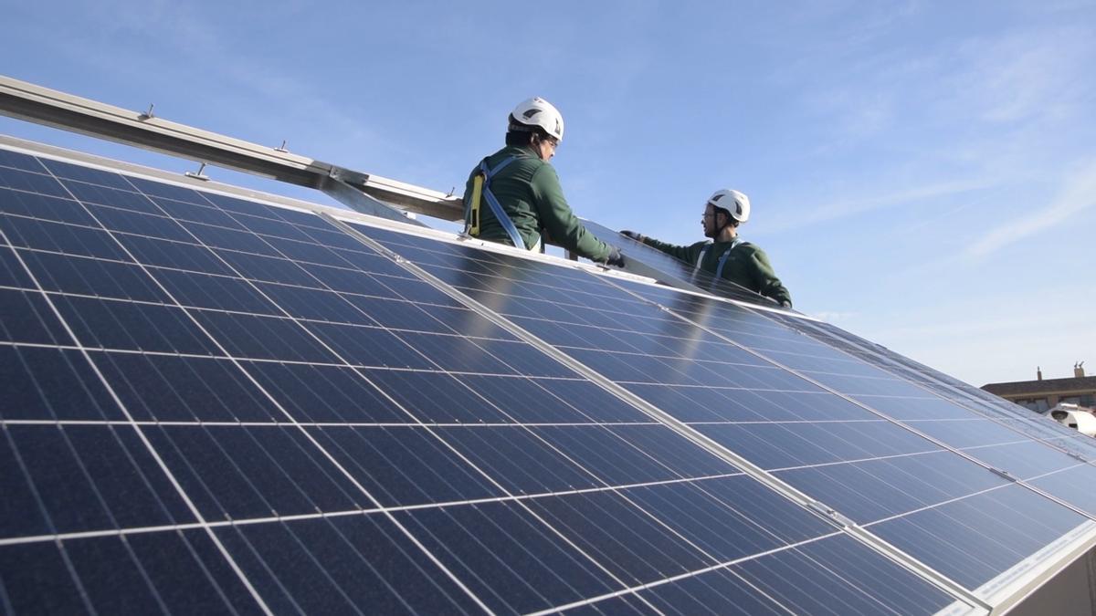 Dos operarios instalan paneles solares para el autoconsumo