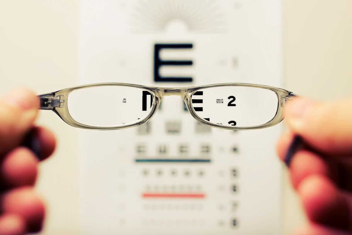 Unas lentes ante el cartel de revisión de la vista. 